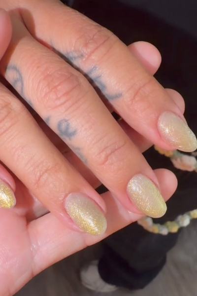 A closeup image of Karol G's shimmery gold Coachella manicure
